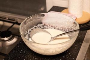 Zubereitung der Masse für Pfannkuchen. Milch mit Mehl in einer Schüssel vermischen. foto