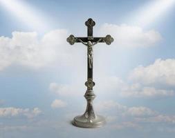 Kreuz im Himmel. eine Statuette des gekreuzigten Jesus. das symbol der christlichen religion vor blauem himmel mit wolken. Erlösung. foto