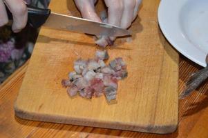 Hering mit einem Messer auf einem Küchenbrett schneiden