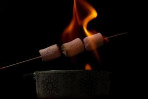 Marshmallows aufgespießt süß in Flammen