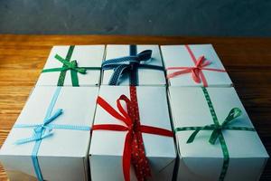 Stapel weiße Geschenkboxen mit Bändern auf Holztisch. foto