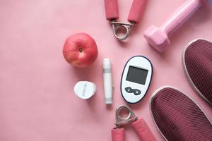 Diabetische Messinstrumente, Schuh und Apfel auf rosa Hintergrund foto