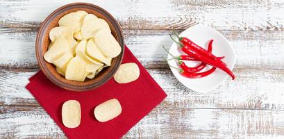 Kartoffelchips auf Teller, Peperoni und rote Serviette auf Holztisch nachahmen - Platz kopieren foto