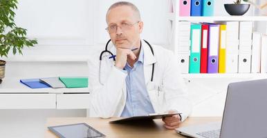 Arzt sitzt in einer Arztpraxis, Krankenversicherung