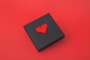 Geschenk-Blackbox mit Herzen auf rotem Grund. Nahaufnahme Kopie Raum foto