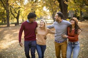 gemischtrassige junge Leute, die im Herbstpark spazieren gehen foto