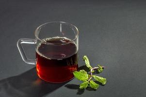 Tasse Tee, Minze und Zitrone auf dunklem Hintergrund