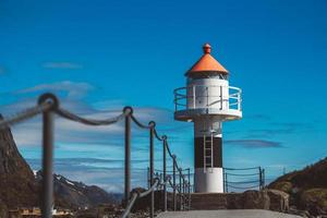 Leuchtturm auf dem Pier vor dem Hintergrund der Berge und des blauen Himmels auf den Lofoten. Platz für Text oder Werbung