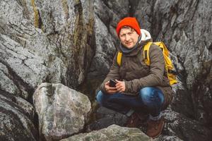 Reisender Mann hält Smartphone in den Händen vor dem Hintergrund von Bergen und Felsen. Platz für Text oder Werbung