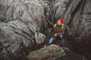 Reisender, der ein Selbstporträt mit einem Smartphone vor dem Hintergrund von Bergen und Felsen macht. Platz für Text oder Werbung