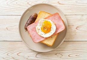 Brot gerösteter Käse überbackener Schinken und Spiegelei mit Schweinswurst foto