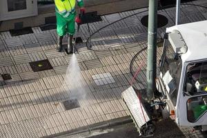 Kehrmaschine, die einen Bürgersteig mit Hochdruckwasserstrahlmaschine eines Reinigungsfahrzeugs wäscht. Straßenpflege foto
