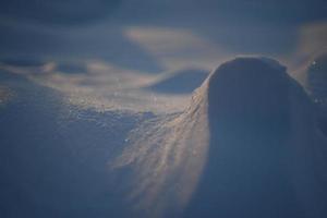 verschneite Landschaften und Schnee Nahaufnahme in Sonnenstrahlen. Gras und Gegenstände im Schnee. foto