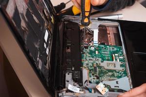 Zauberer repariert Laptop mit Werkzeugen und Händen foto