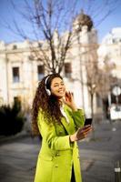 junge Frau hört Musik mit Smartphone auf der Straße
