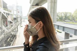 Schöne Frau, die eine Anti-Staub-Maske trägt, schützt die Luftverschmutzung und um 2,5 Uhr auf der Straße foto
