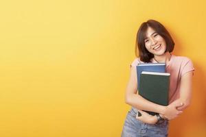 schöne asiatische Studentin glücklich auf gelbem Hintergrund foto