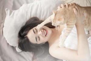 schöne asiatische katzenliebhaberin spielt mit katze in ihrem zimmer