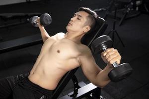 muskulöser Fitness-Mann-Bodybuilder trainiert mit Hanteln im Fitnessstudio foto