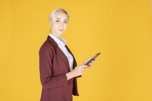 Geschäftsfrau benutzt Tablet im Studio gelben Hintergrund foto