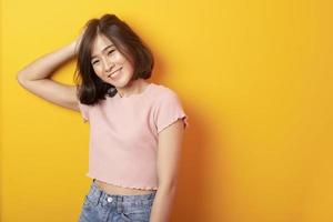 schöne asiatische Studentin glücklich auf gelbem Hintergrund foto