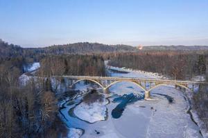 Wintersaison Antenne von oben nach unten Blick auf eine Brücke mit einer geraden Straße über den Fluss? foto