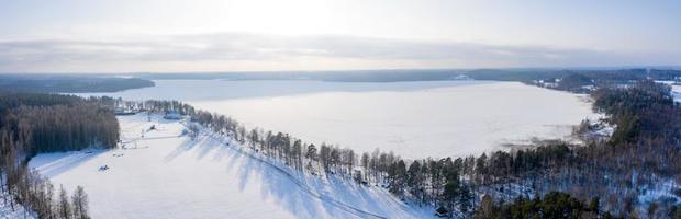 Luftaufnahme der Winterlandschaft, Panorama des zugefrorenen Sees mitten im Wald. Winter Wunderland.