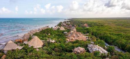 luftige küste von tulum am strand mit einem magischen karibischen meer und kleinen hütten an der küste. foto