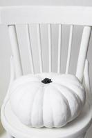 Halloween und ein weißer Kürbis auf einem Stuhl auf weißem Hintergrund