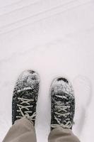 Mann steht in schneebedeckten Stiefeln nach Schneesturm foto