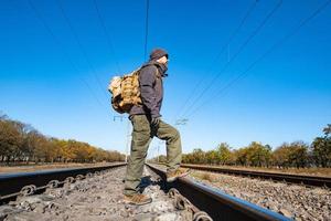 männlicher Reisender mit taktischer und militärischer Ausrüstung geht allein an sonnigen Tagen foto