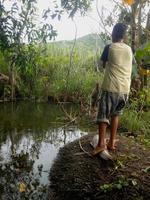 kleiner Junge, der tagsüber im Sumpf fischt foto