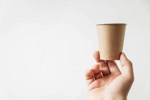 Männerhand hält einen Pappbecher auf weißem Hintergrund foto