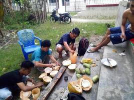Indonesien, Juli 2021 - eine Gruppe Jugendlicher genießt nachmittags Kokosnüsse im Vorgarten des Hauses foto