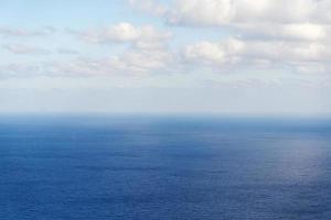 schöne weiße wolken am blauen himmel über ruhigem meer mit sonnenreflexion, bali indonesien. ruhige Meeresharmonie der ruhigen Wasseroberfläche. sonniger Himmel und ruhiger blauer Ozean. foto
