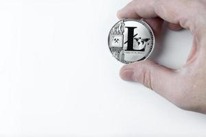 Hand hält einen Litecoin auf weißem Hintergrund. foto