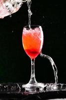 alkoholische Cocktails bestehend aus roten Fruchtsäften und Sodawasser. von einem professionellen Barkeeper in ein Glas Wein gegossen.