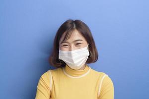 Porträt einer jungen schönen asiatischen Frau, die eine chirurgische Maske über Studiohintergrund trägt, Covid19-Pandemie und Luftverschmutzung foto