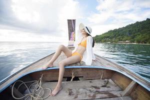 Blick auf eine Frau im Badeanzug, die auf einem traditionellen thailändischen Longtail-Boot über schöne Berge und das Meer, die Phi-Phi-Inseln, thailand, genießt