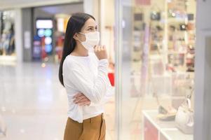 Frau mit Schutzmaske Einkaufen unter Covid-19-Pandemie im Einkaufszentrum, Protokoll zur sozialen Distanzierung, neues normales Konzept. foto