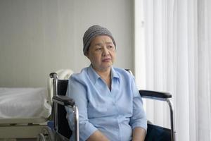 depressive und hoffnungslose asiatische krebspatientin mit kopftuch im krankenhaus.
