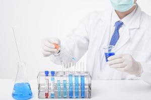 Nahaufnahme des Wissenschaftlers testet und erforscht einige blaue flüssige Chemikalien im Labor isoliert auf weißem Hintergrund.