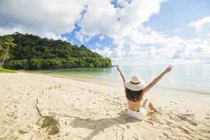 Eine glückliche schöne Frau im gelben Bikini, die am Strand-, Sommer- und Ferienkonzept genießt und sich entspannt foto