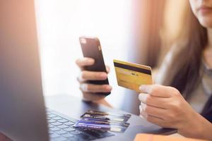 Frauenhand hält Kreditkarte und kauft online ein