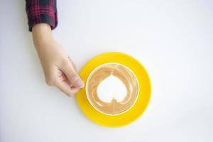Heiße Latte Art in gelber Tasse auf dem Schreibtisch foto
