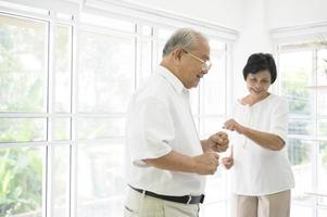 Fröhliches älteres asiatisches Rentnerehepaar tanzt und genießt die Musik im Wohnzimmer zu Hause, Gesundheitskonzept foto