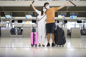 Ein asiatisches Paar trägt eine Schutzmaske auf dem internationalen Flughafen, reist unter der Covid-19-Pandemie, Sicherheitsreisen, Protokoll zur sozialen Distanzierung, neues normales Reisekonzept.
