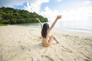 Eine glückliche schöne Frau im gelben Bikini, die am Strand-, Sommer- und Ferienkonzept genießt und sich entspannt
