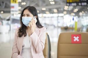 Eine Geschäftsfrau trägt eine Schutzmaske auf dem internationalen Flughafen, reist unter der Covid-19-Pandemie, Sicherheitsreisen, Protokoll zur sozialen Distanzierung, neues normales Reisekonzept foto