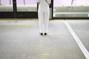 Eine junge Frau steht auf dem U-Bahnsteig, trägt Gesichtsmaske, Covid-19-Schutz, neues normales Reisekonzept.